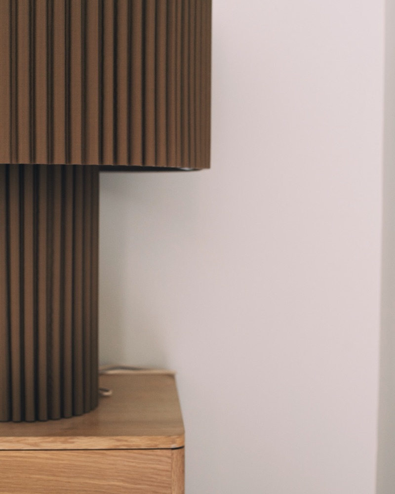 Une lampe en bois cannelé posée sur un meuble en chêne, dans un bureau de La Maison.