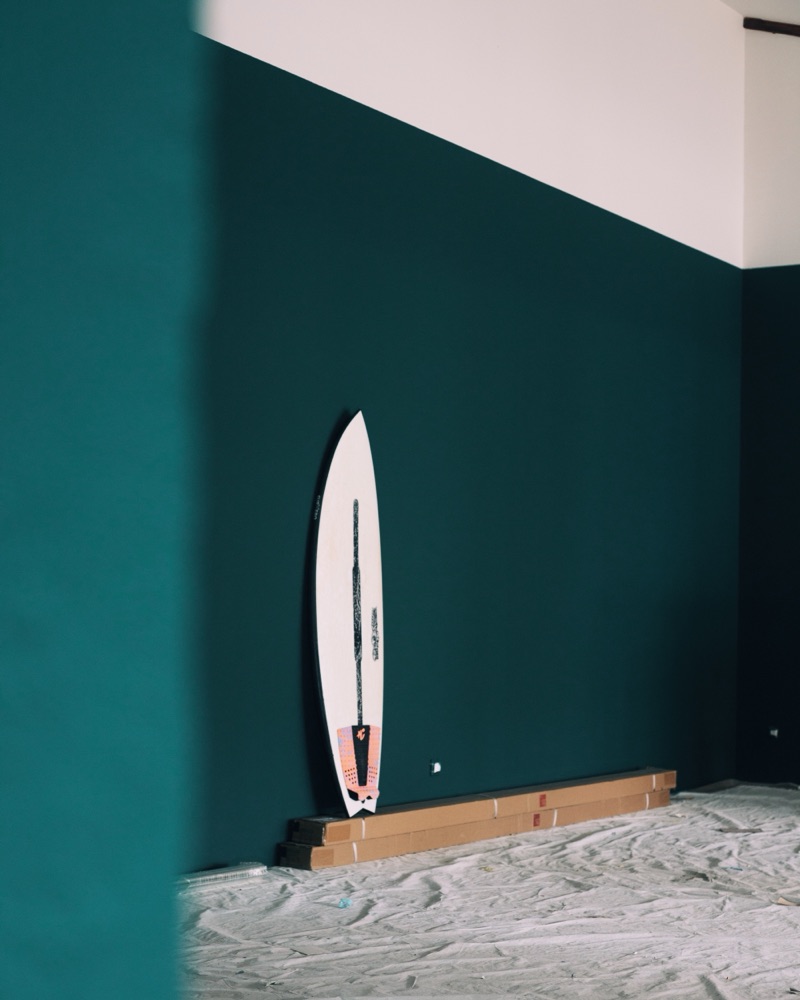 Une planche de surf contre le mur vert de La Surf Room, à la Bibi House, à Biarritz.