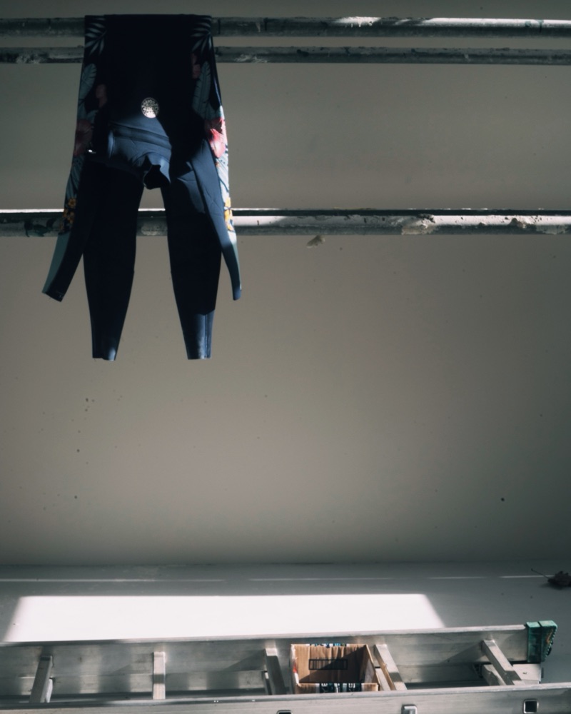 Une combinaison de surf qui sèche dans la lumière des Vestiaires.